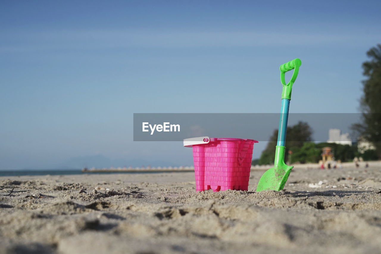 Bucket and shovel at sandy against sky