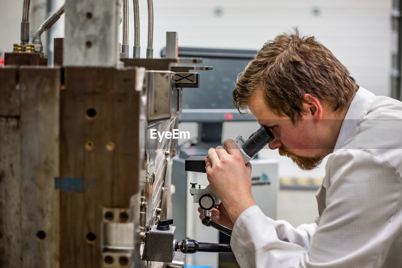 SIDE VIEW OF MAN WORKING IN MACHINE