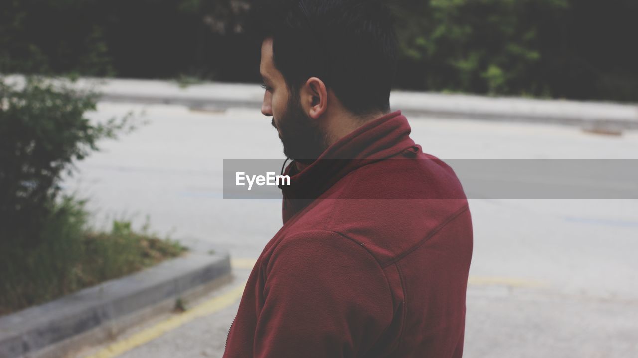 Side view of young man standing on road