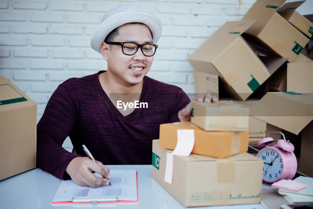 PORTRAIT OF YOUNG MAN SITTING ON TABLE IN BOX