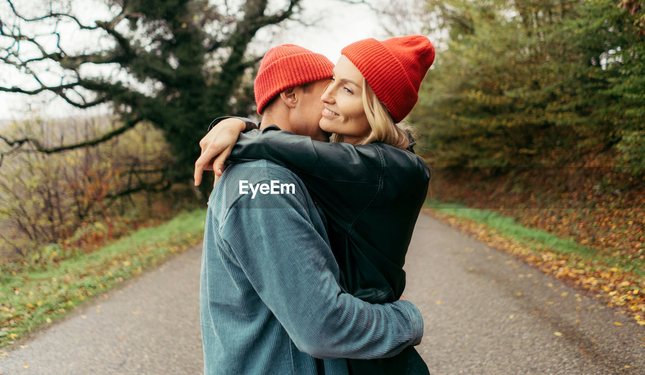 Young attractive woman hugging her boyfriend in the countryside on the road.