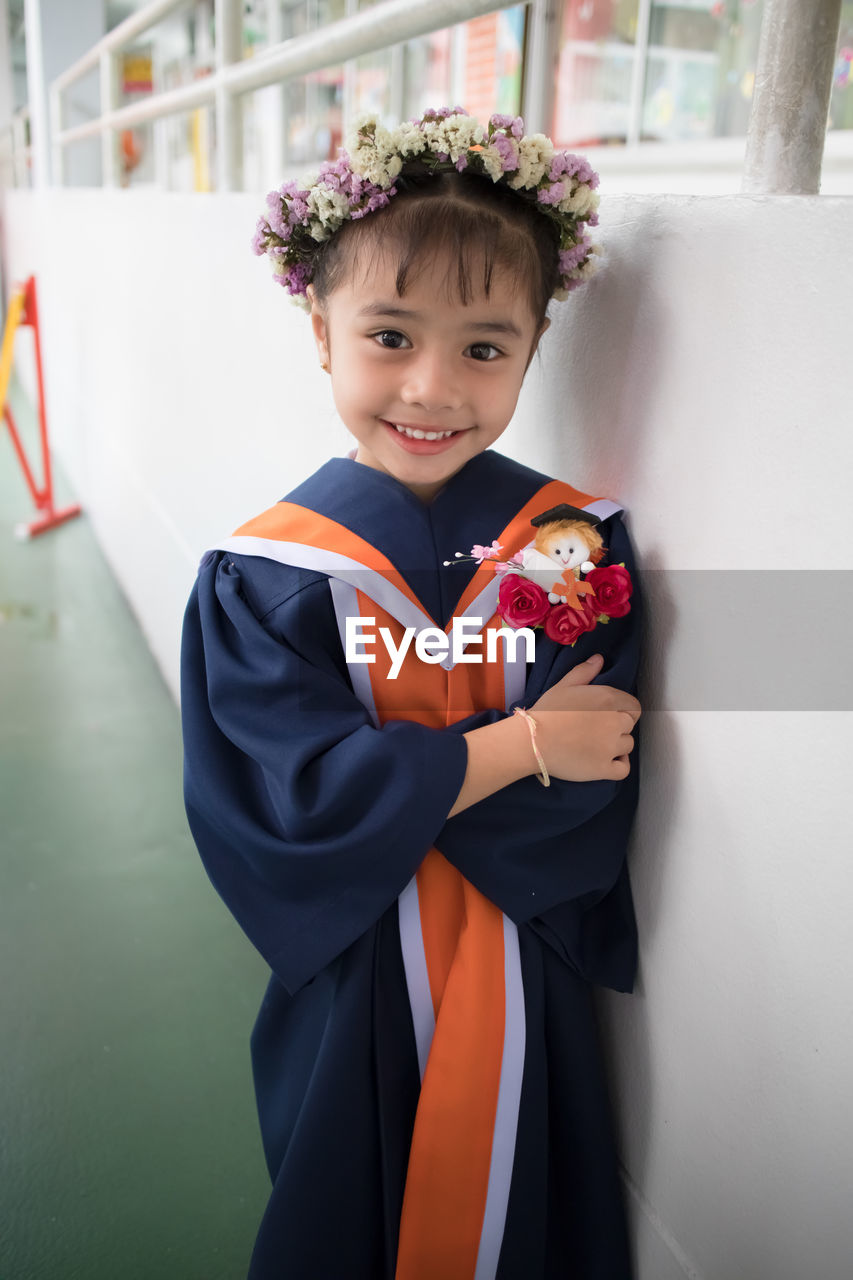 Portrait of smiling cute girl standing by wall