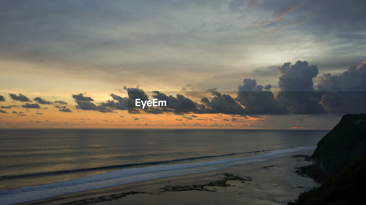 SCENIC VIEW OF BEACH AGAINST SKY AT SUNSET