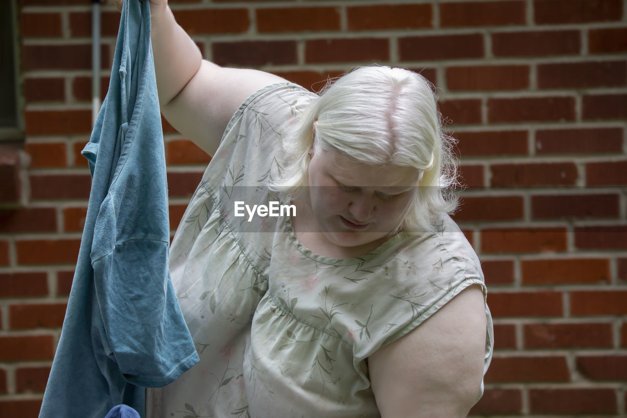 Albino woman folding clothes outdoors