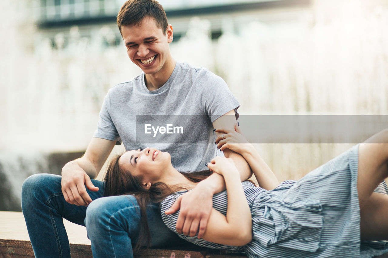 Girlfriend lying on boyfriend lap against fountain