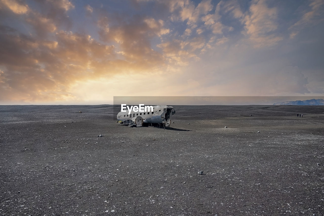 View of damaged airplane wreck at black sand beach in solheimasandur in sunset