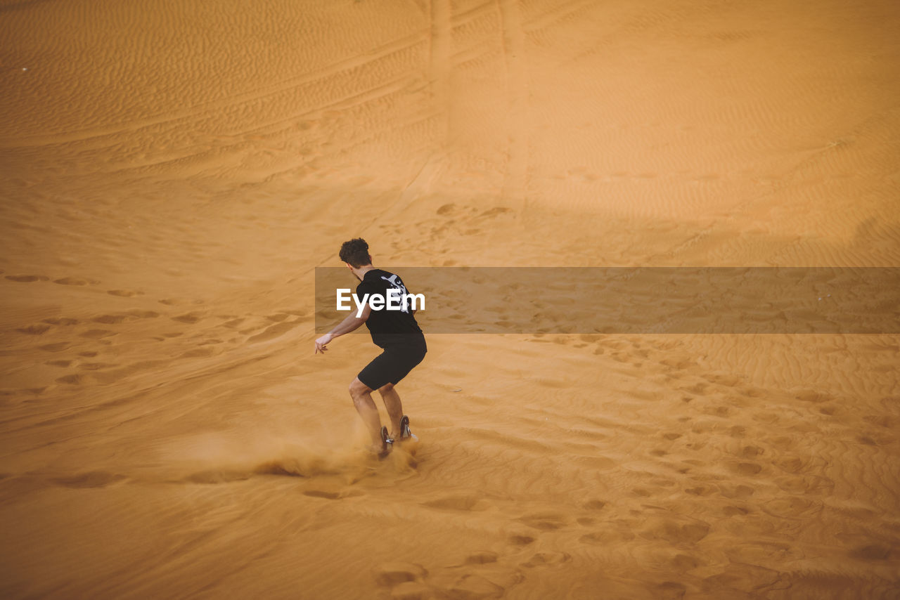 FULL LENGTH OF BOY PLAYING ON SAND