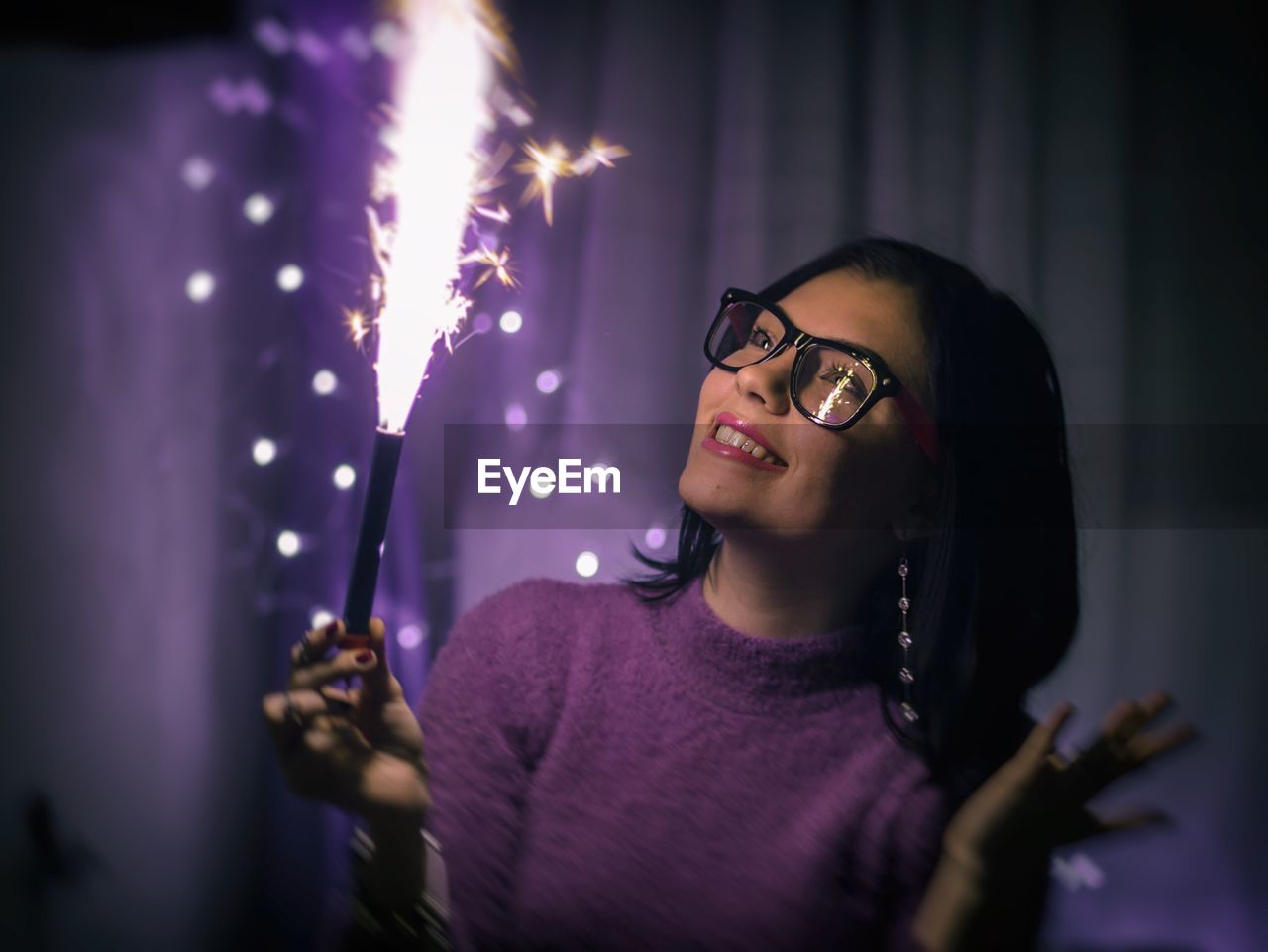 Smiling young woman with illuminated firework at night