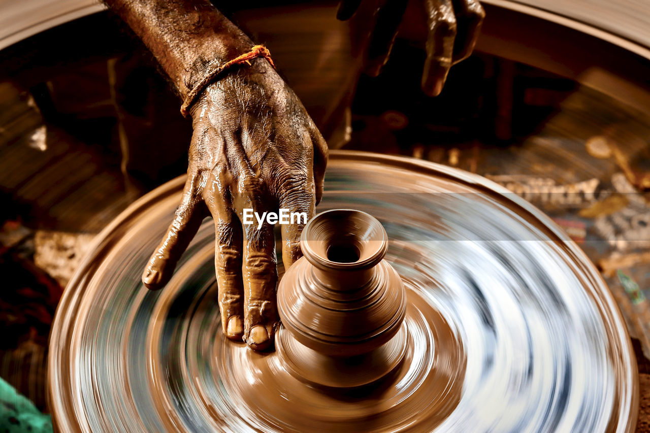 A slow shutter shot of a potter hand making a pot from a pottery wheel at hubli, karnataka, india.