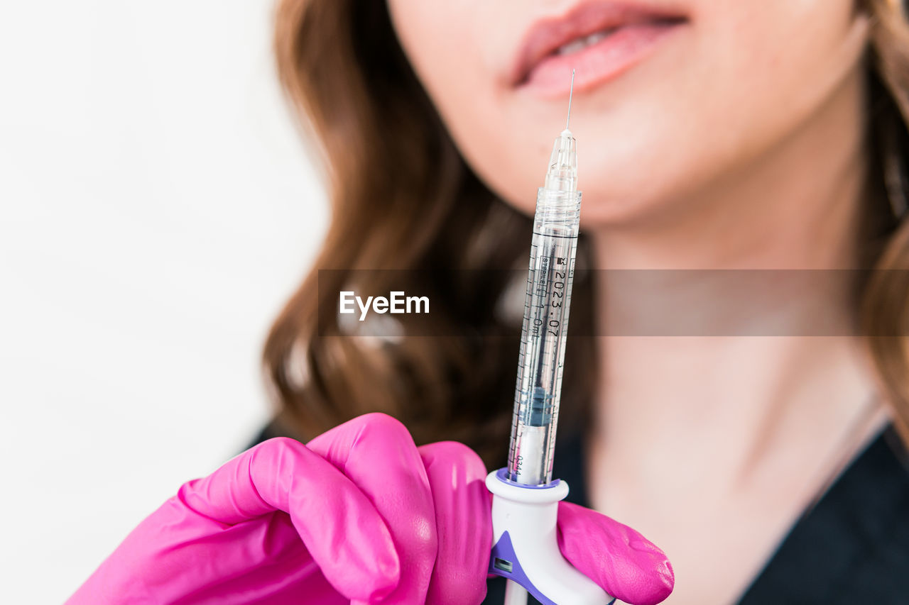midsection of doctor holding syringe against white background