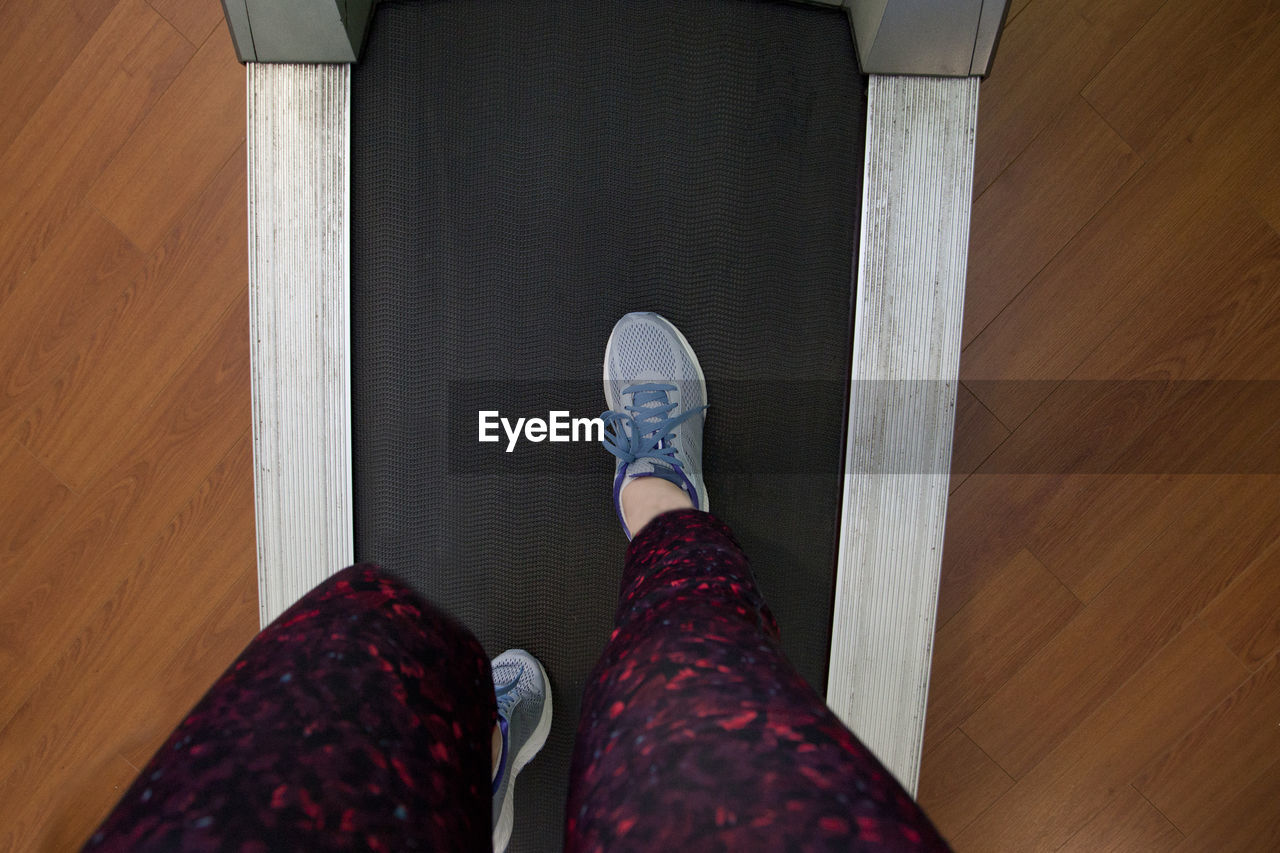 LOW SECTION OF WOMAN STANDING ON WOODEN FLOOR