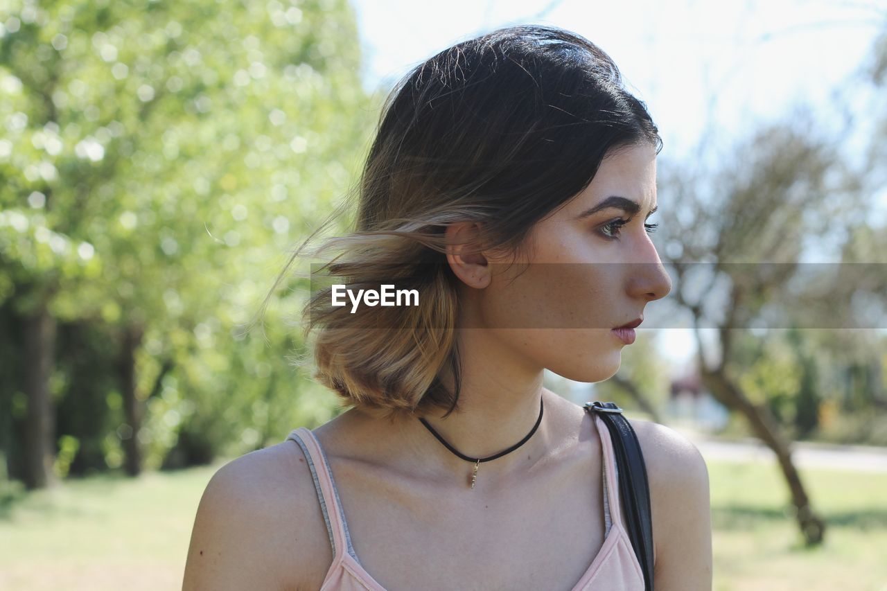 Close-up of thoughtful young woman standing at park