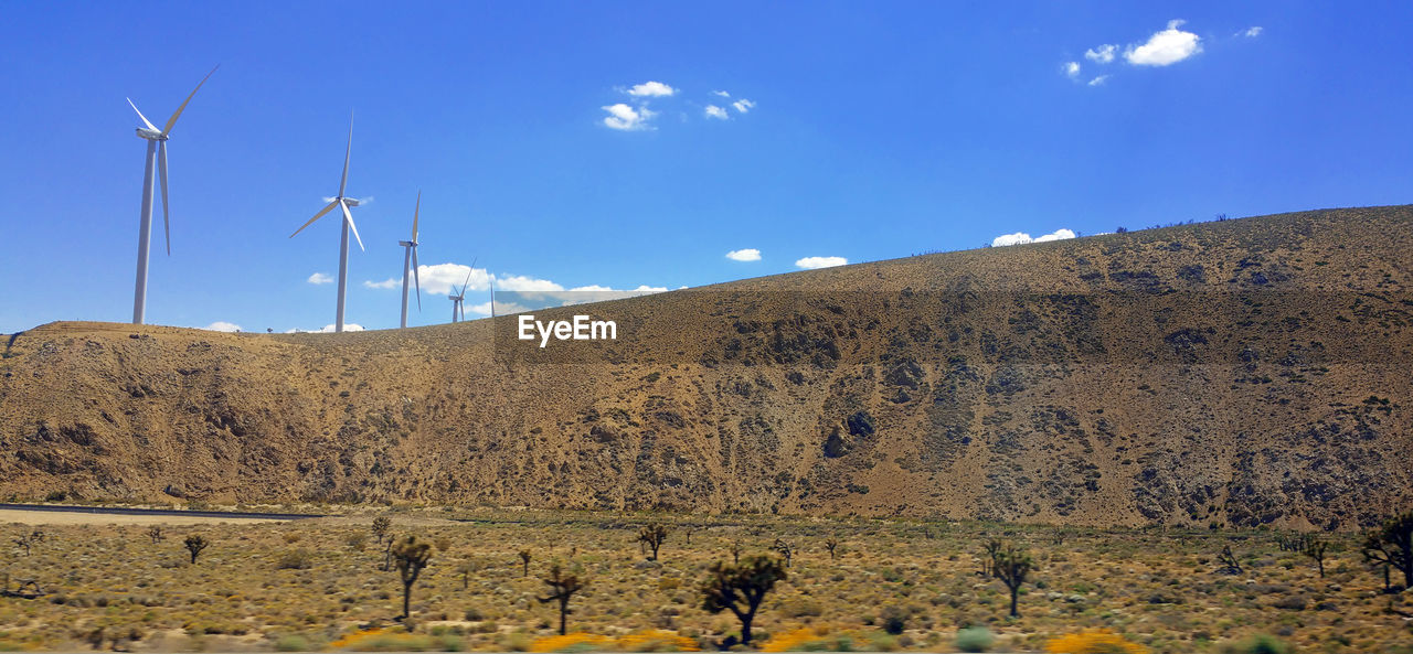 Wind turbines on land against sky