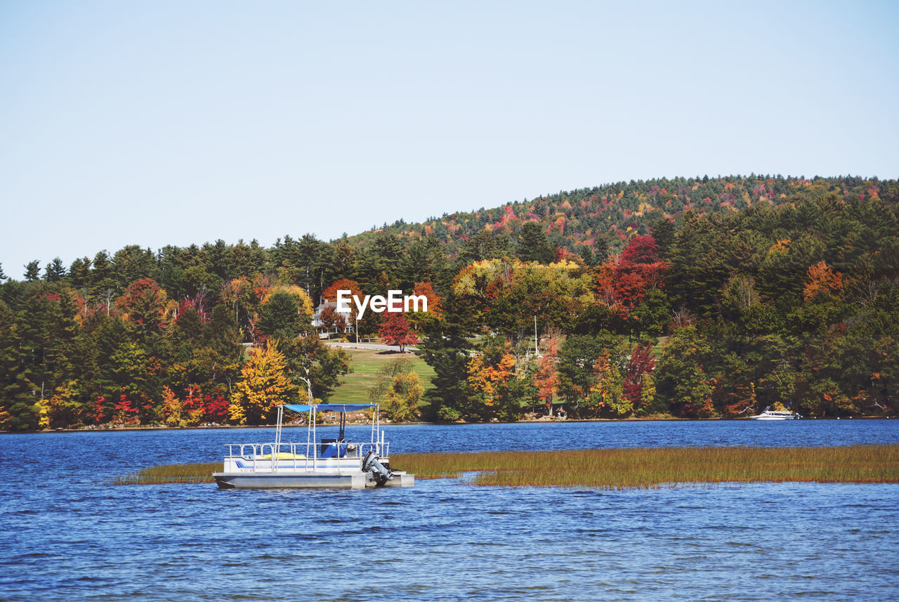 Boat sailing in river against clear sky