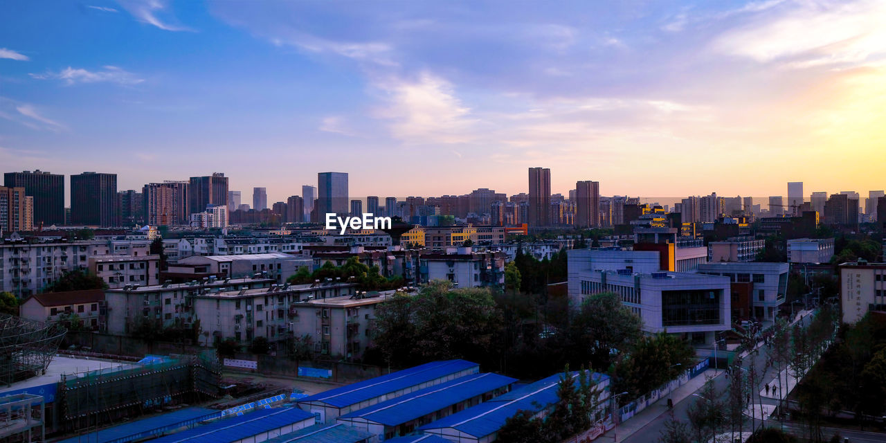 HIGH ANGLE VIEW OF BUILDINGS AGAINST SKY AT SUNSET