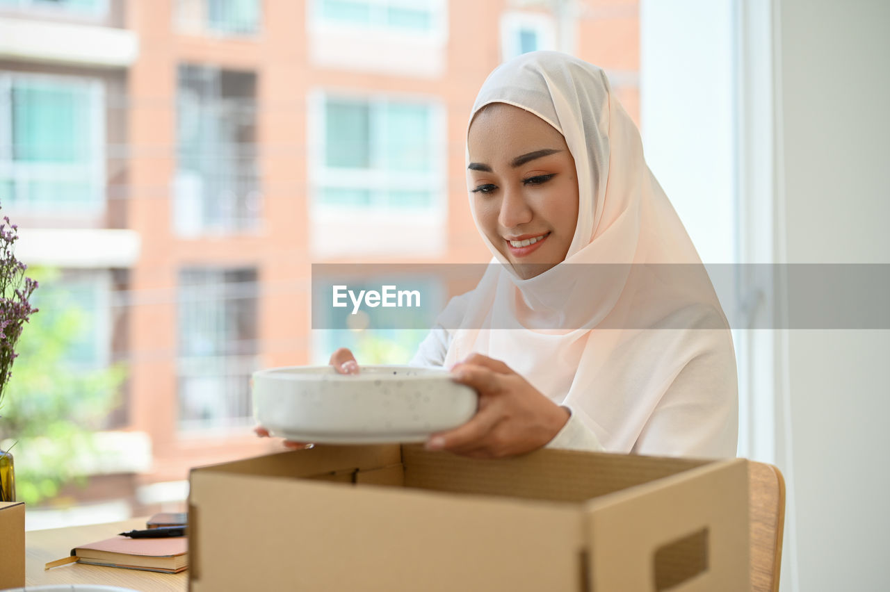 Businesswoman wearing hijab opening box