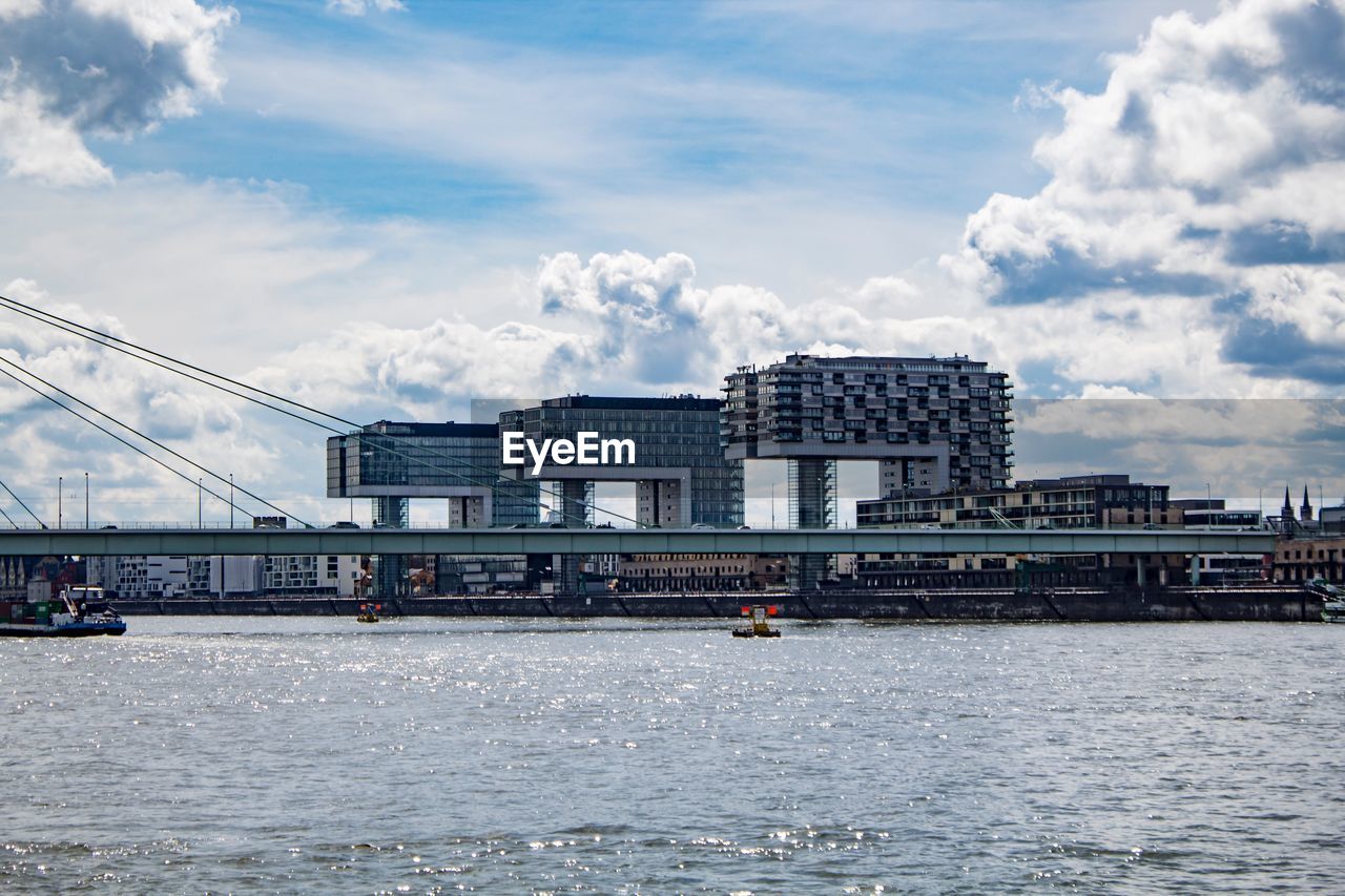 Bridge over river in city against sky