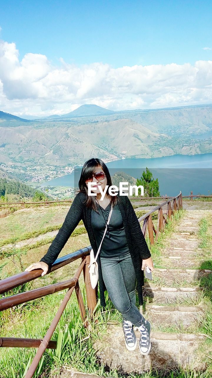 Portrait of woman standing on steps against sky