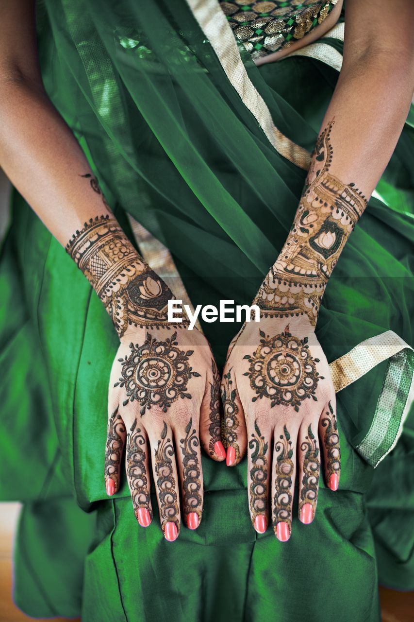 Midsection of woman showing heena tattoo on hand