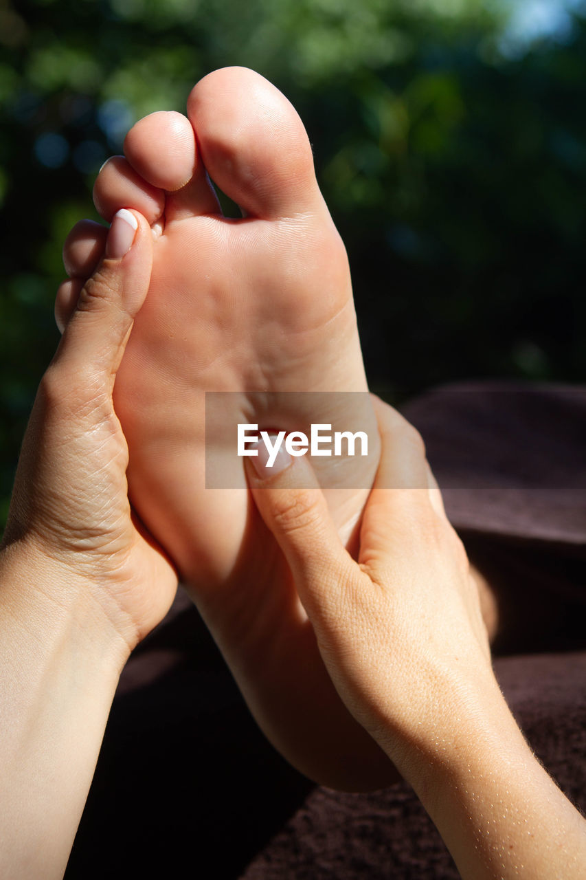 Cropped hands giving foot massage to woman