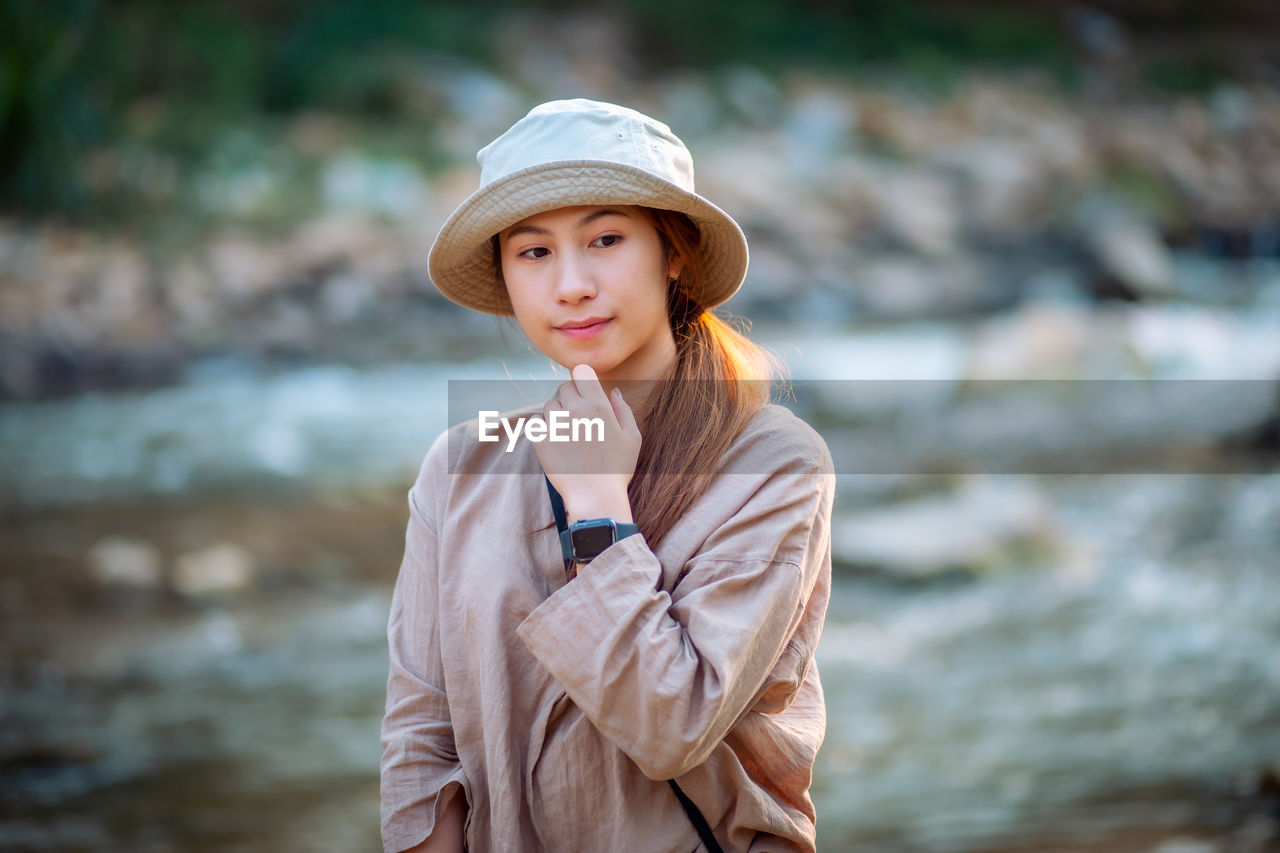 Portrait of beautiful young woman standing against water