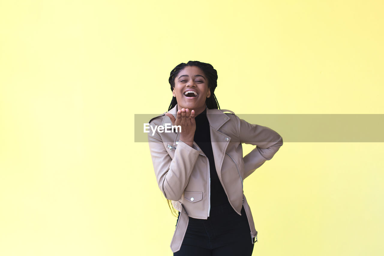 SMILING YOUNG MAN AGAINST YELLOW BACKGROUND