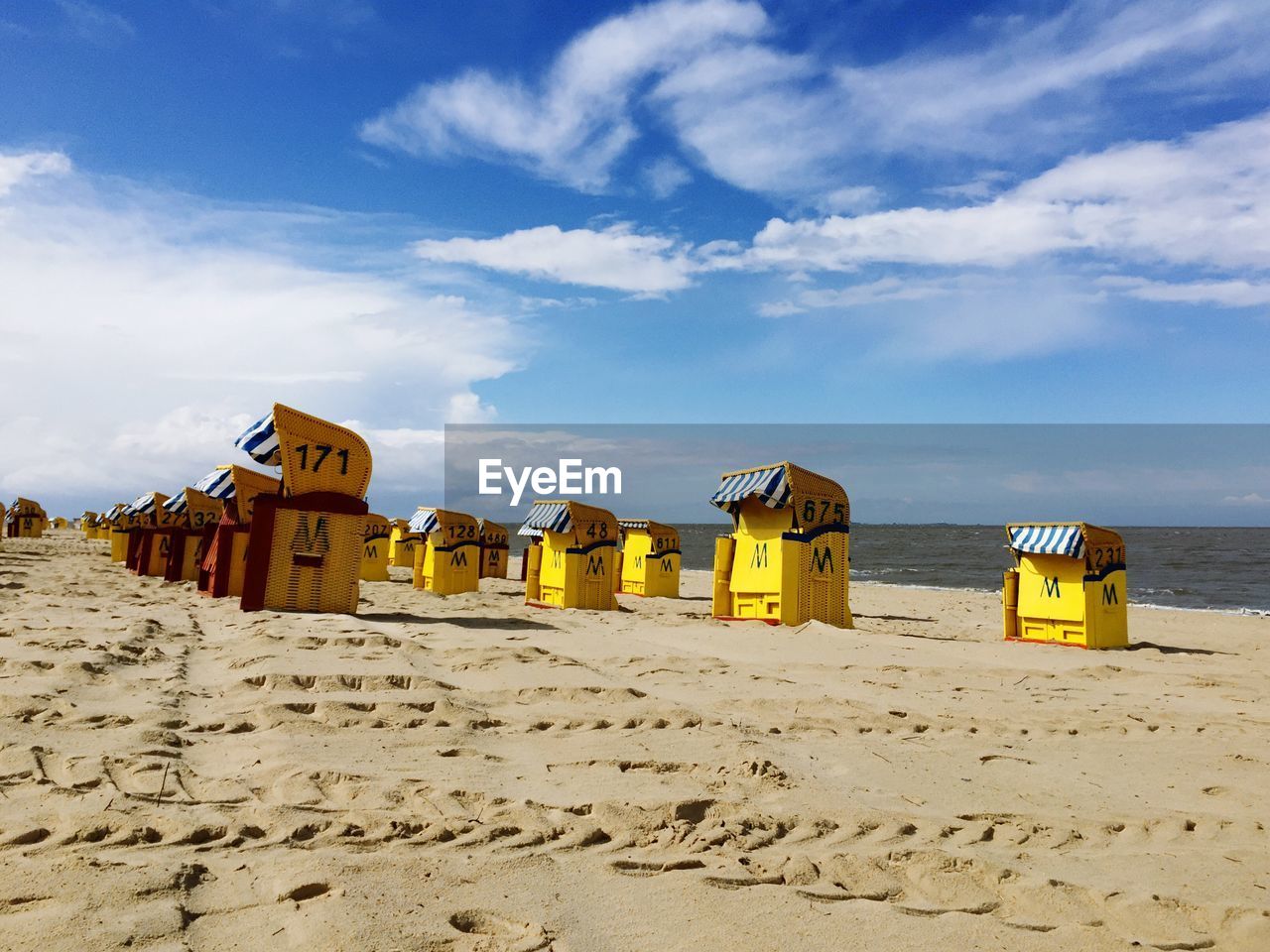 Hooded chairs at beach against sky