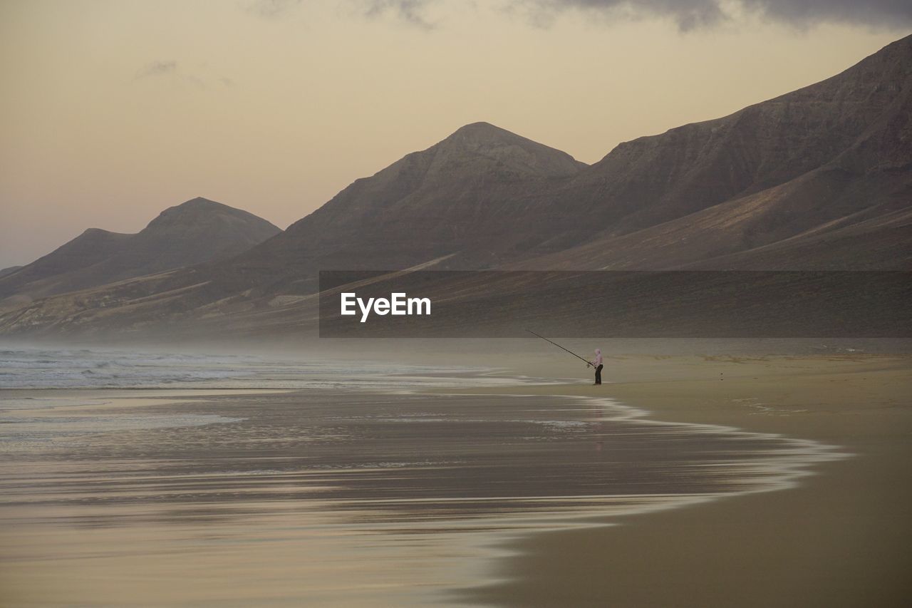 SCENIC VIEW OF SEA AGAINST MOUNTAIN RANGE