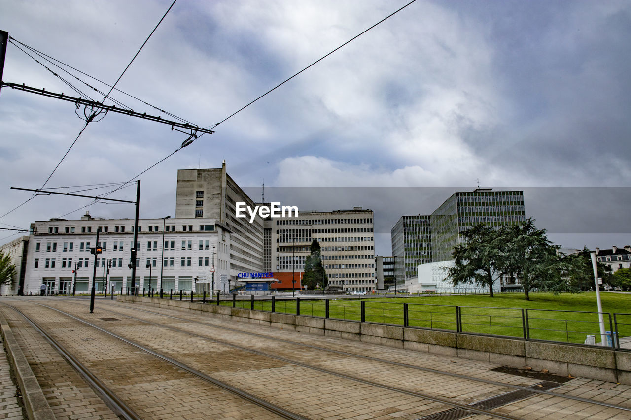 RAILROAD TRACKS BY BUILDINGS AGAINST SKY