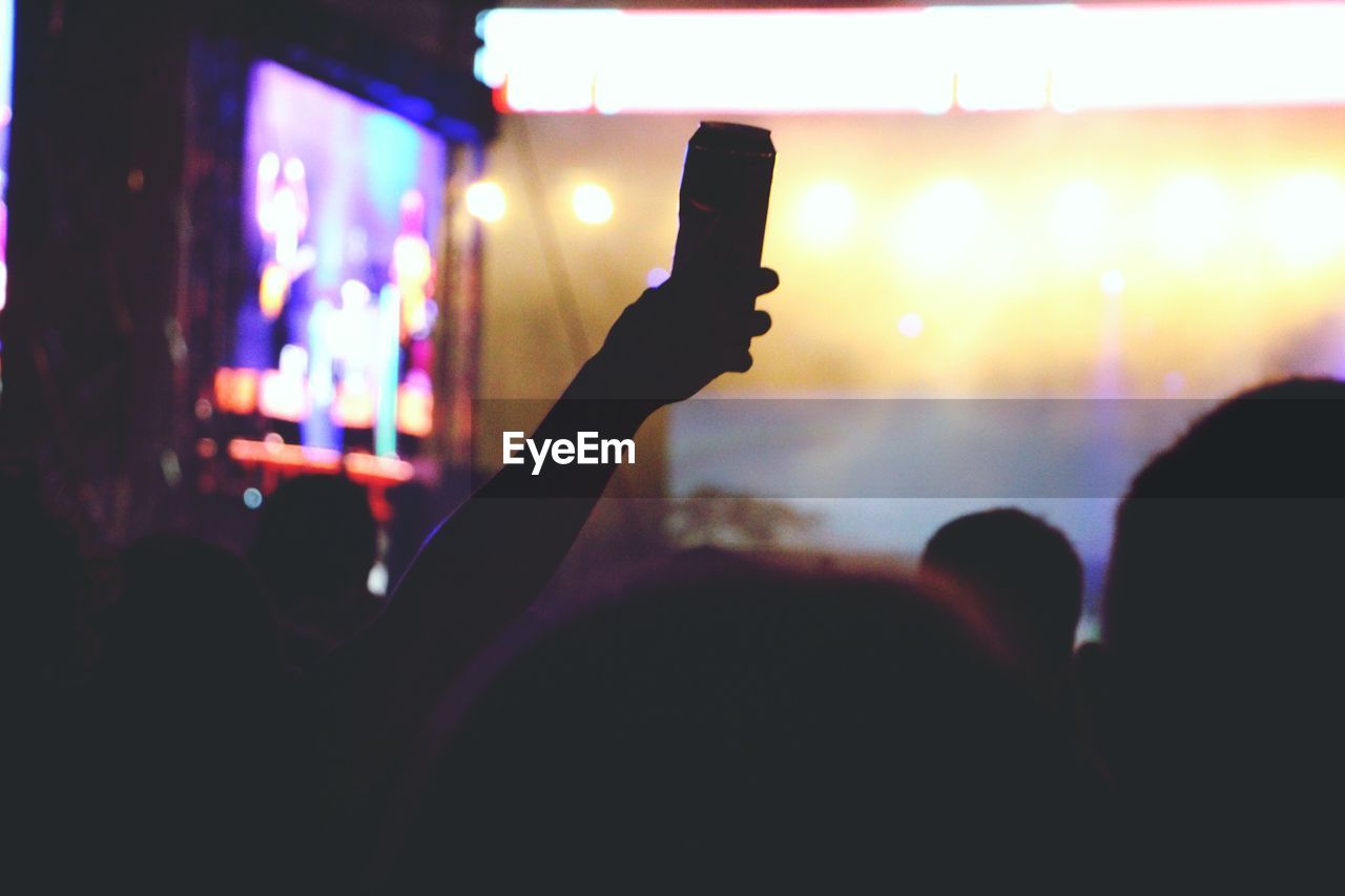 Person holding beer can in concert