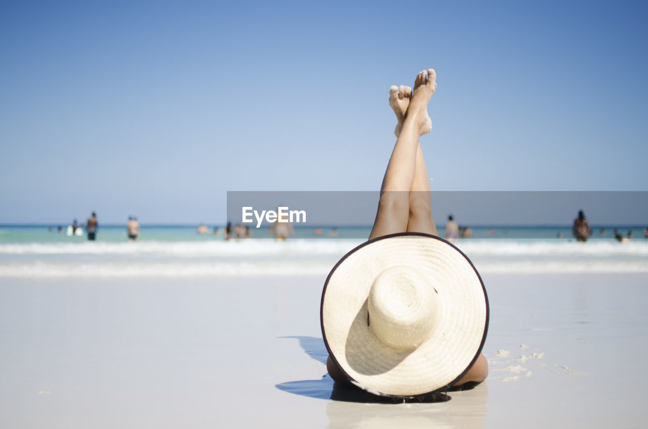 Woman lying at beach against clear sky