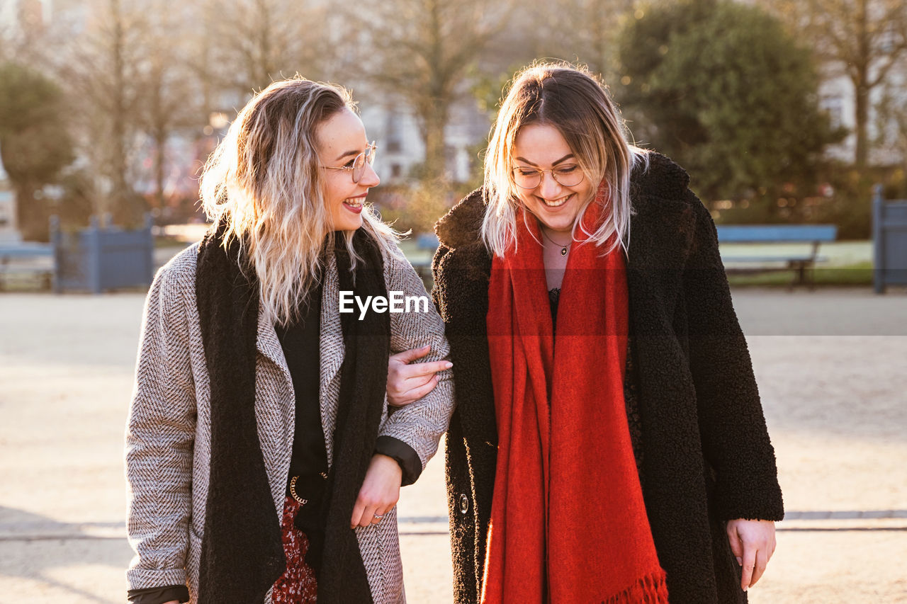 Smiling female friends talking while walking in park