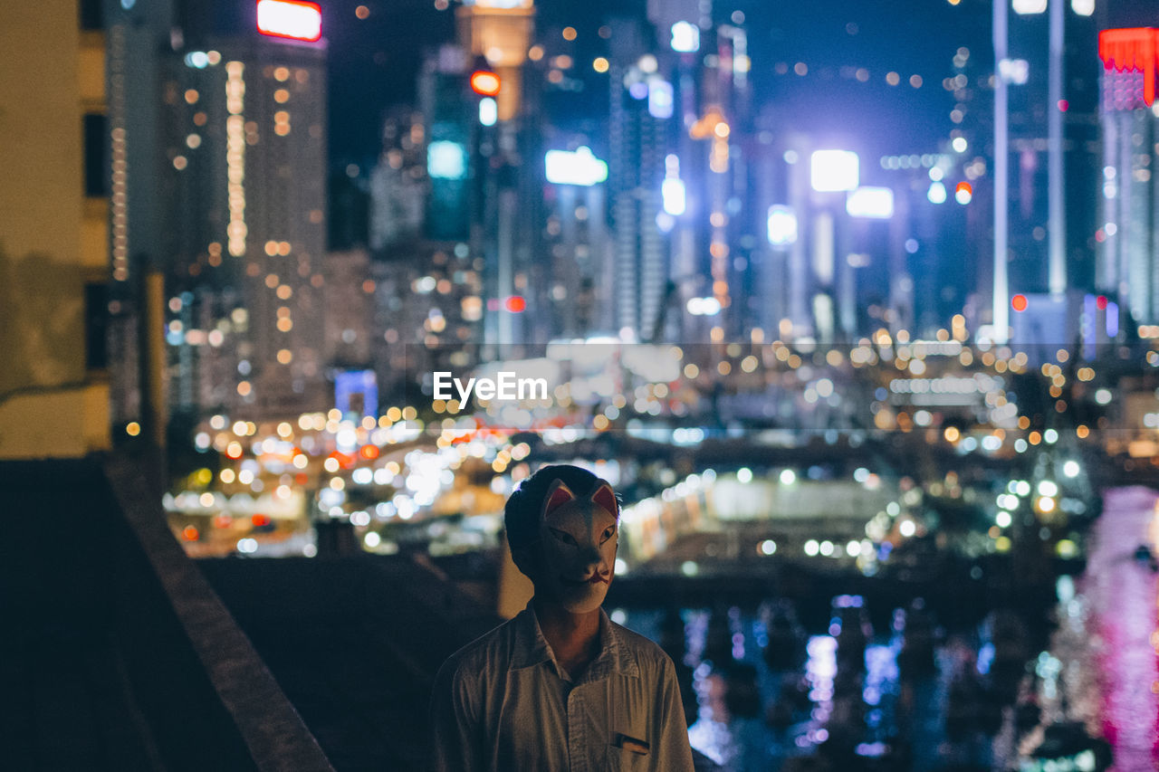 Man wearing mask while standing on city at night