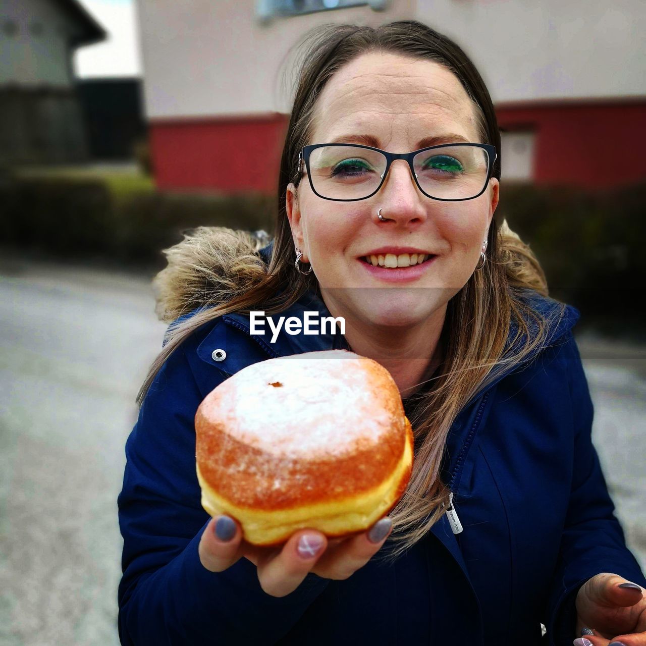 Portrait of woman showing doughnut while standing outdoors