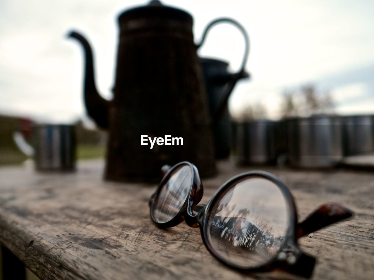 CLOSE-UP OF EYEGLASSES ON TABLE AGAINST SKY