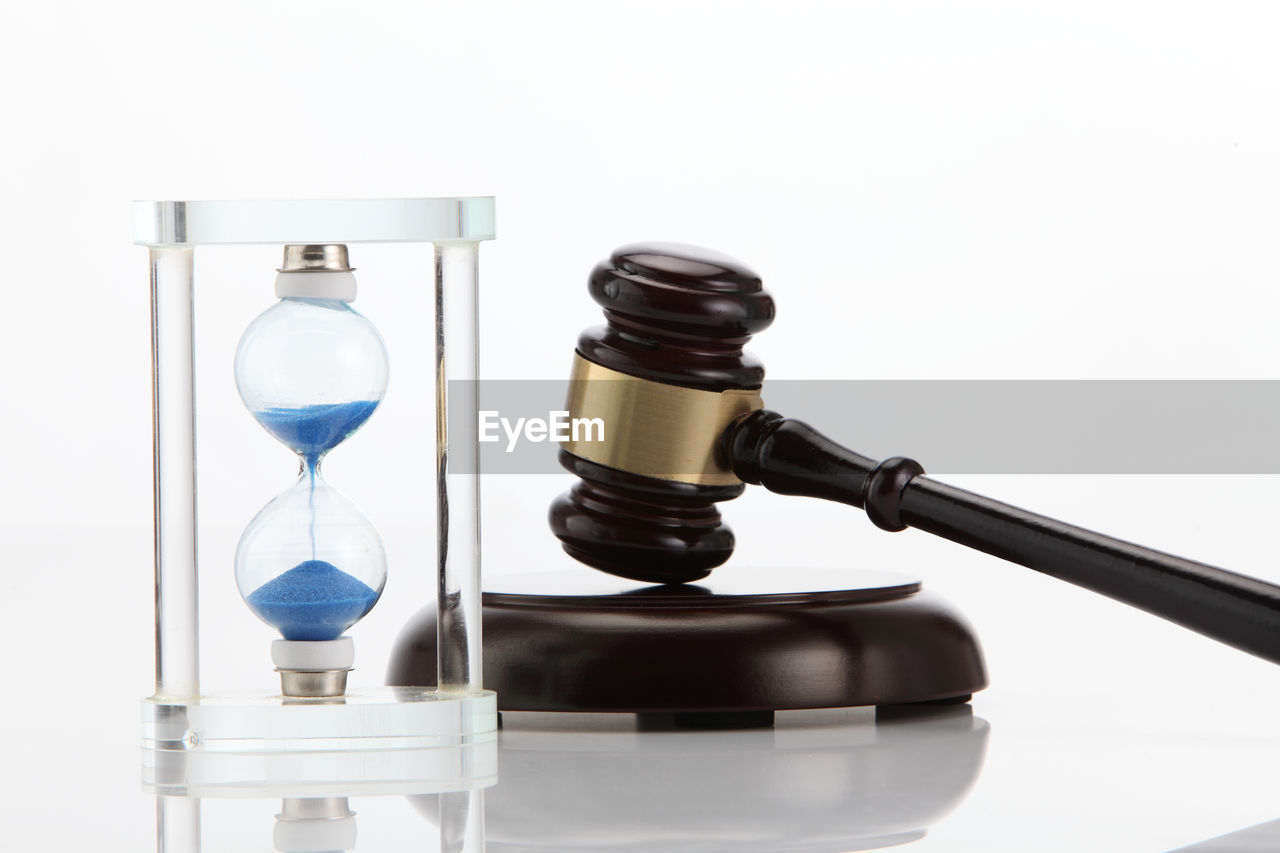 Close-up of gavel with hourglass against white background