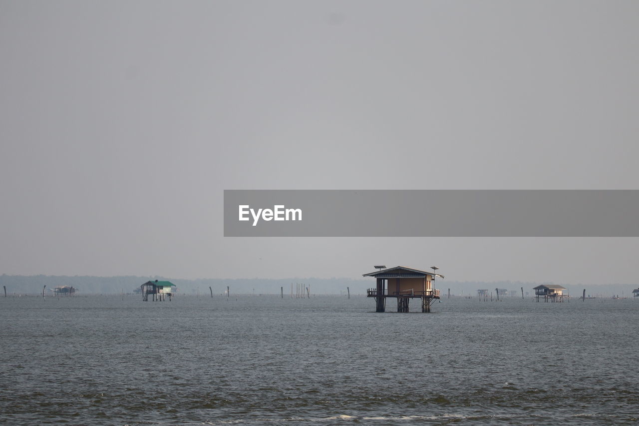 water, sky, horizon, sea, beach, built structure, architecture, coast, nature, land, shore, ocean, hut, building exterior, scenics - nature, copy space, day, building, tranquility, environment, beauty in nature, no people, tranquil scene, body of water, outdoors, clear sky, sand, landscape, lifeguard hut, travel destinations, horizon over water, non-urban scene, travel, house