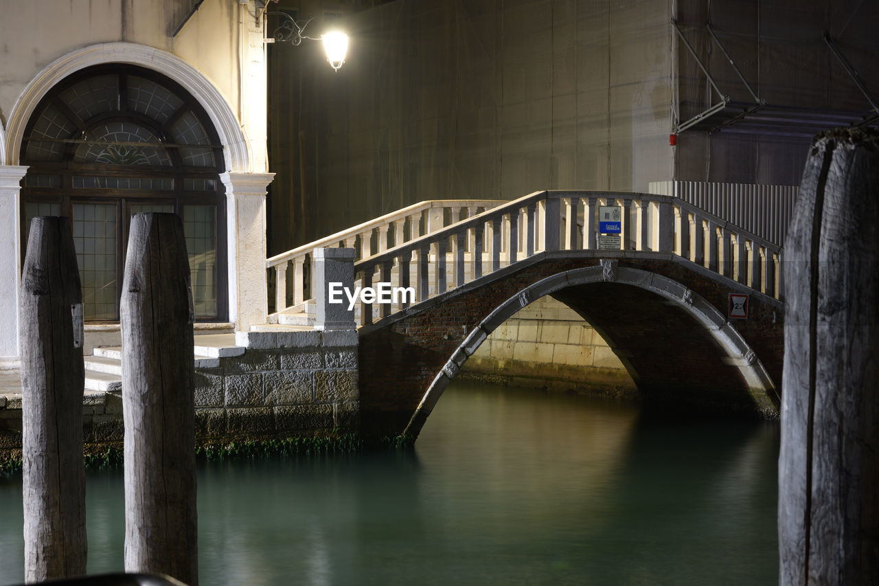 Arch bridge over river at night