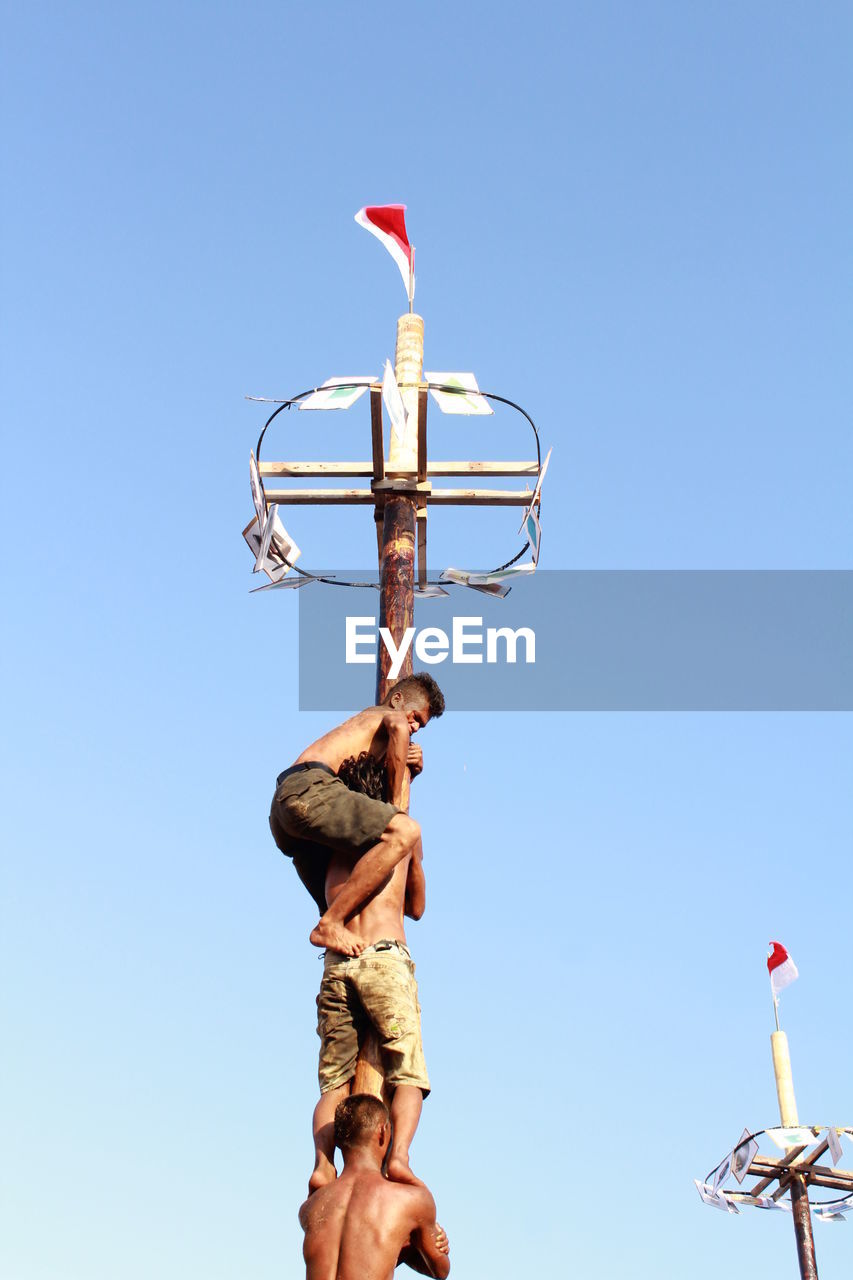 LOW ANGLE VIEW OF MAN AGAINST CLEAR SKY