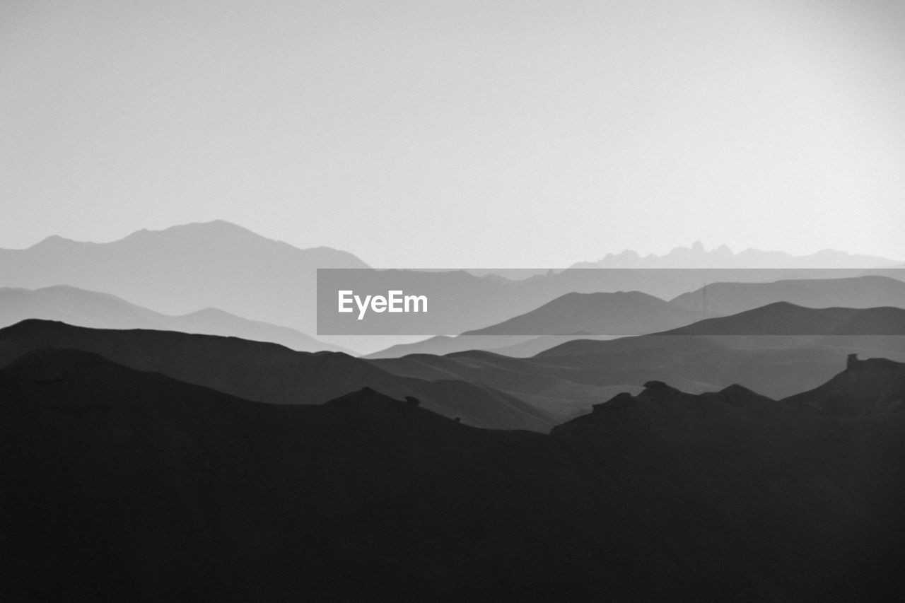 Scenic view of silhouette mountains against clear sky during sunset