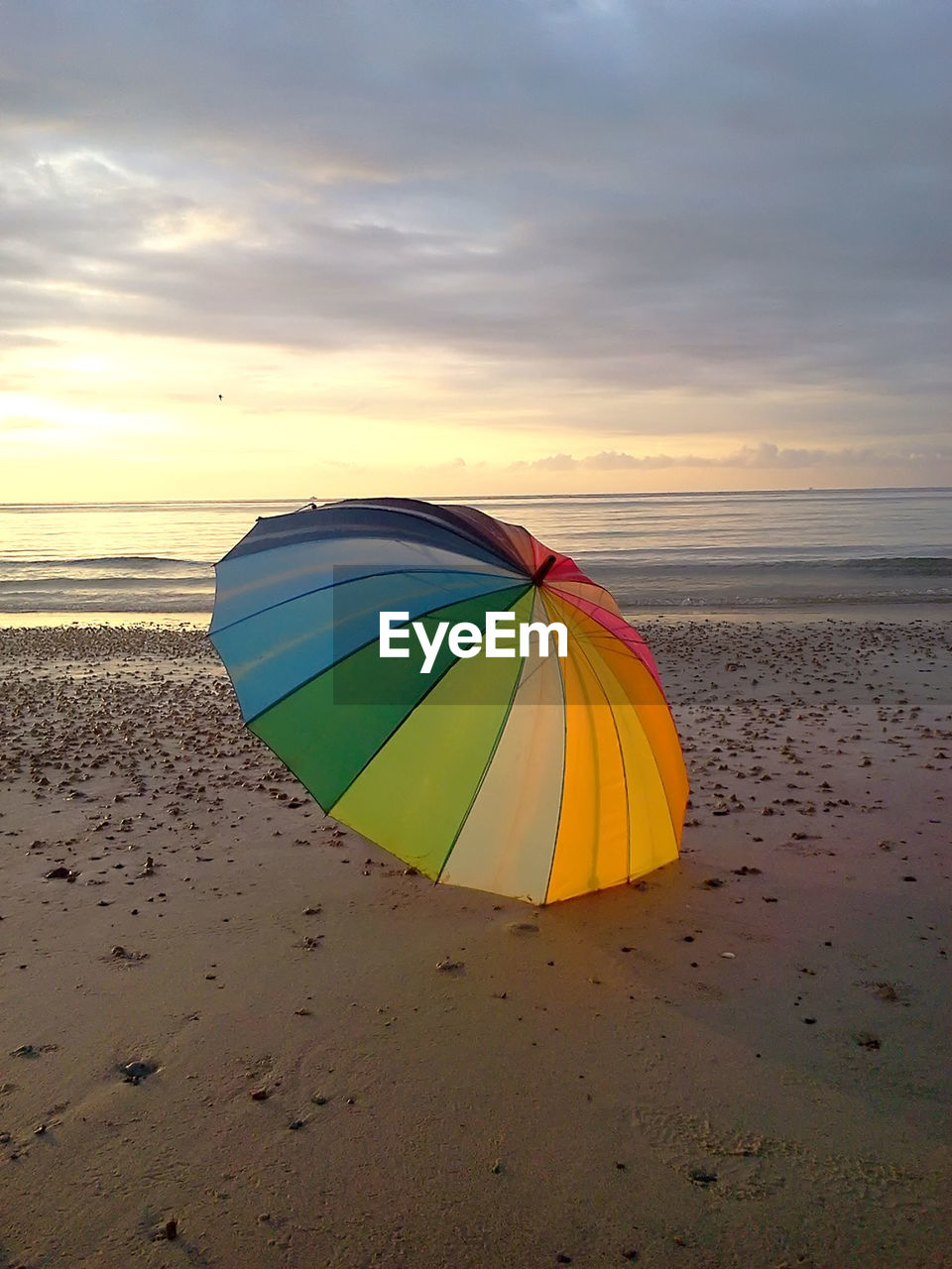 Umbrella at beach against sky during sunset