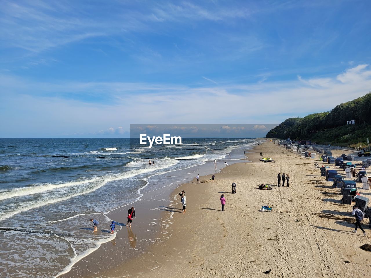 PEOPLE ON BEACH BY SEA AGAINST SKY