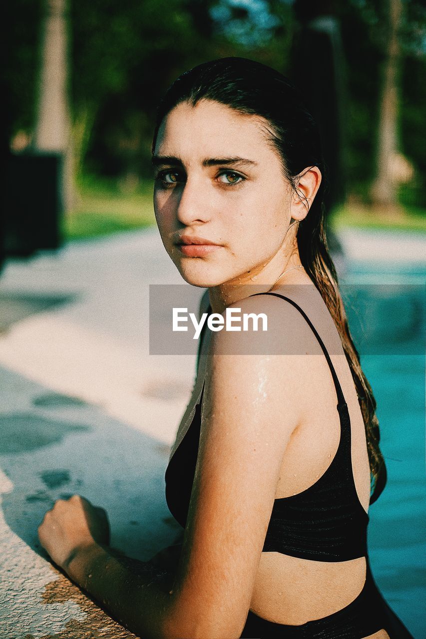 PORTRAIT OF YOUNG WOMAN WITH SWIMMING POOL
