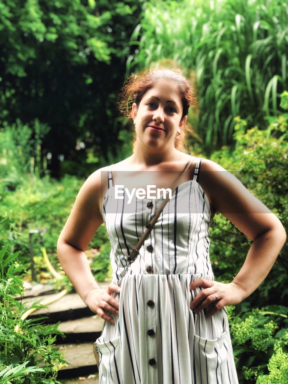 Portrait of a young woman standing against plants