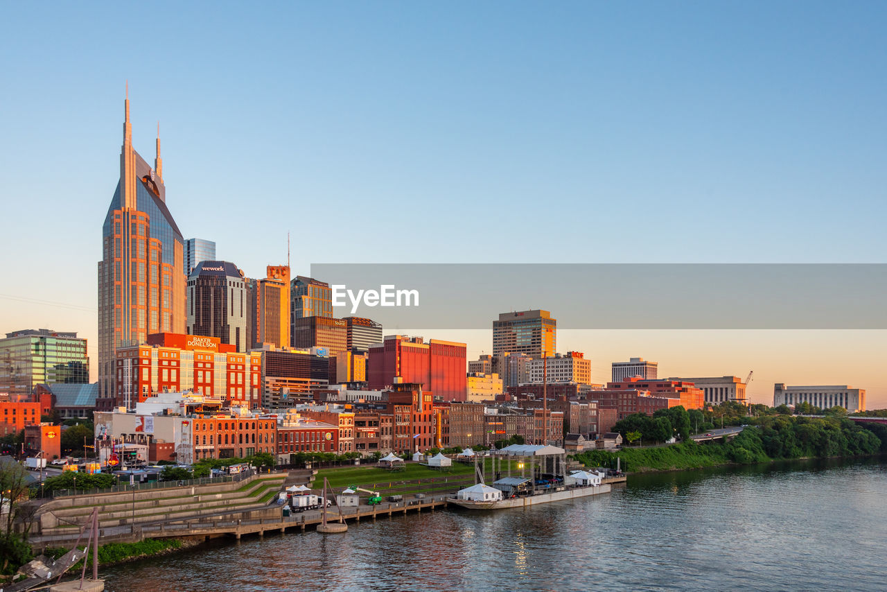 River amidst buildings in city against clear sky