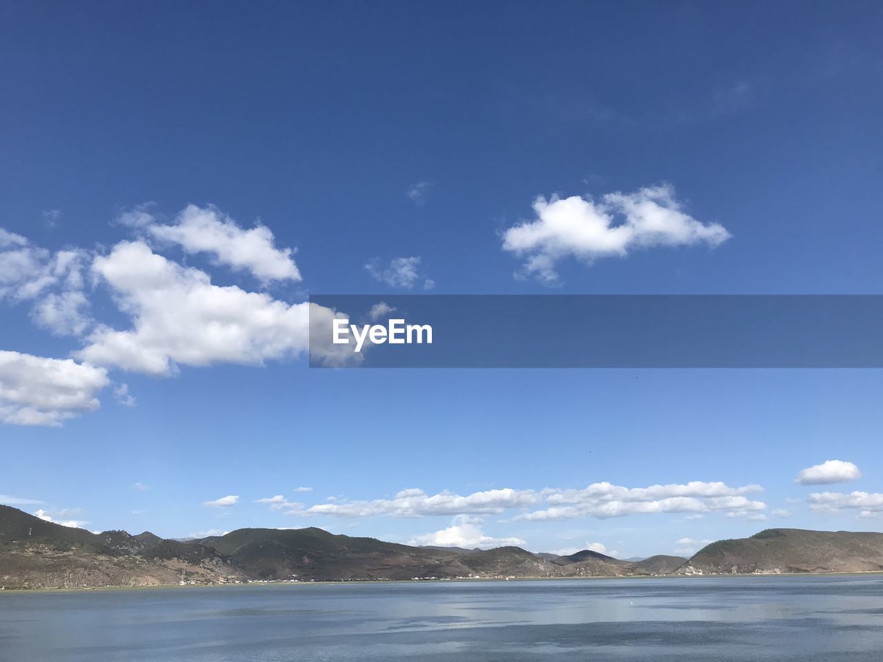 SCENIC VIEW OF SEA BY MOUNTAINS AGAINST BLUE SKY