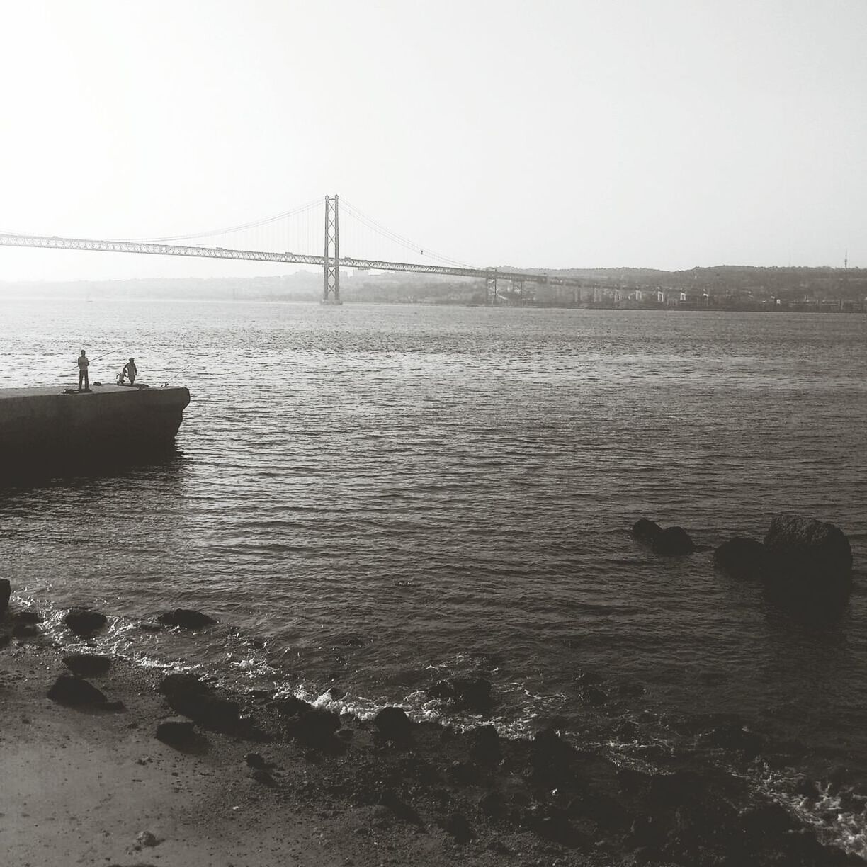 Man standing on retaining wall and fishing at sea