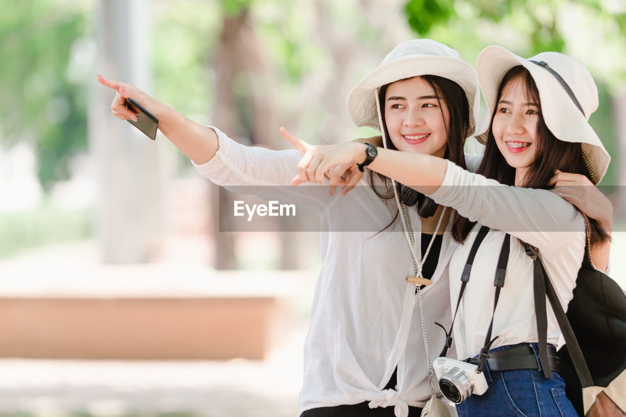 Smiling young women pointing while looking away