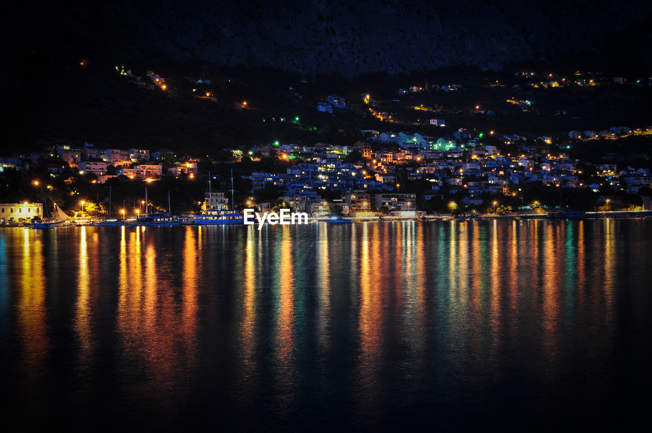 Illuminated cityscape against sky at night