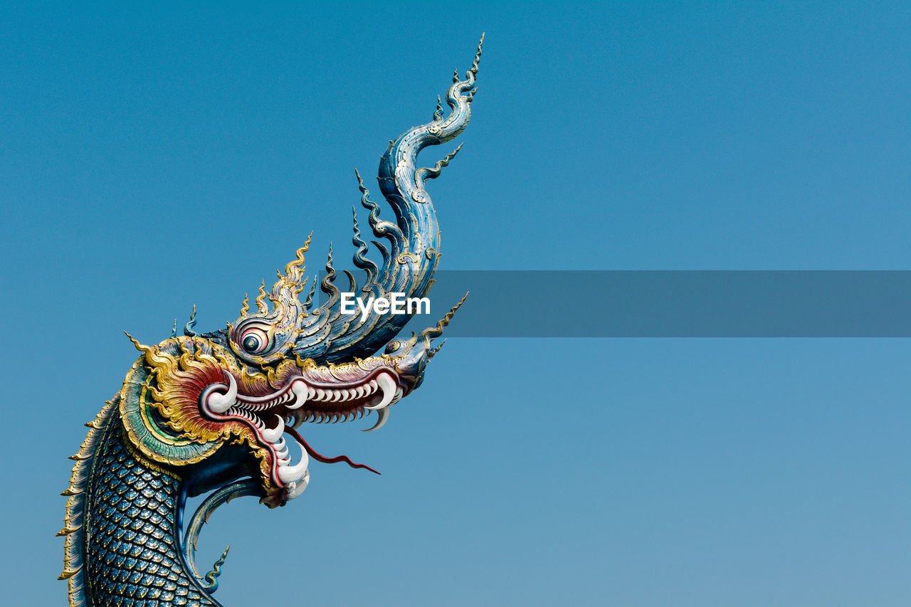 Low angle view of dragon statue at wat rong khun against clear sky